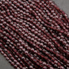 Close-up of a string of maroon beads on a gray surface