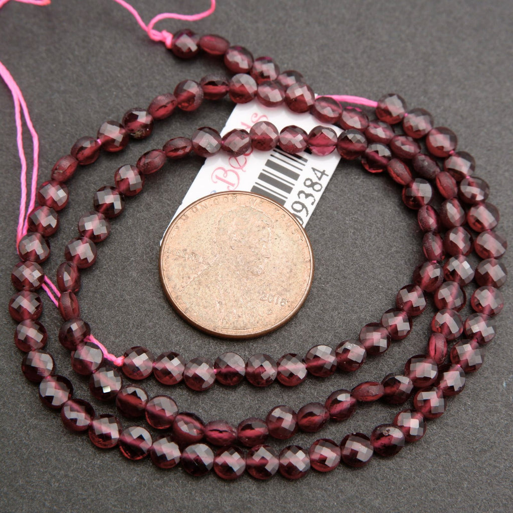 String of red beads with a coin for scale on a gray surface