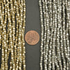 Two strands of faceted beads with a penny for scale on a dark background