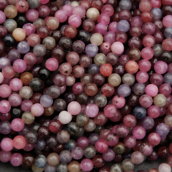 Natural ruby sapphire bead strands displaying shades of burgundy, blue, grey, and pink