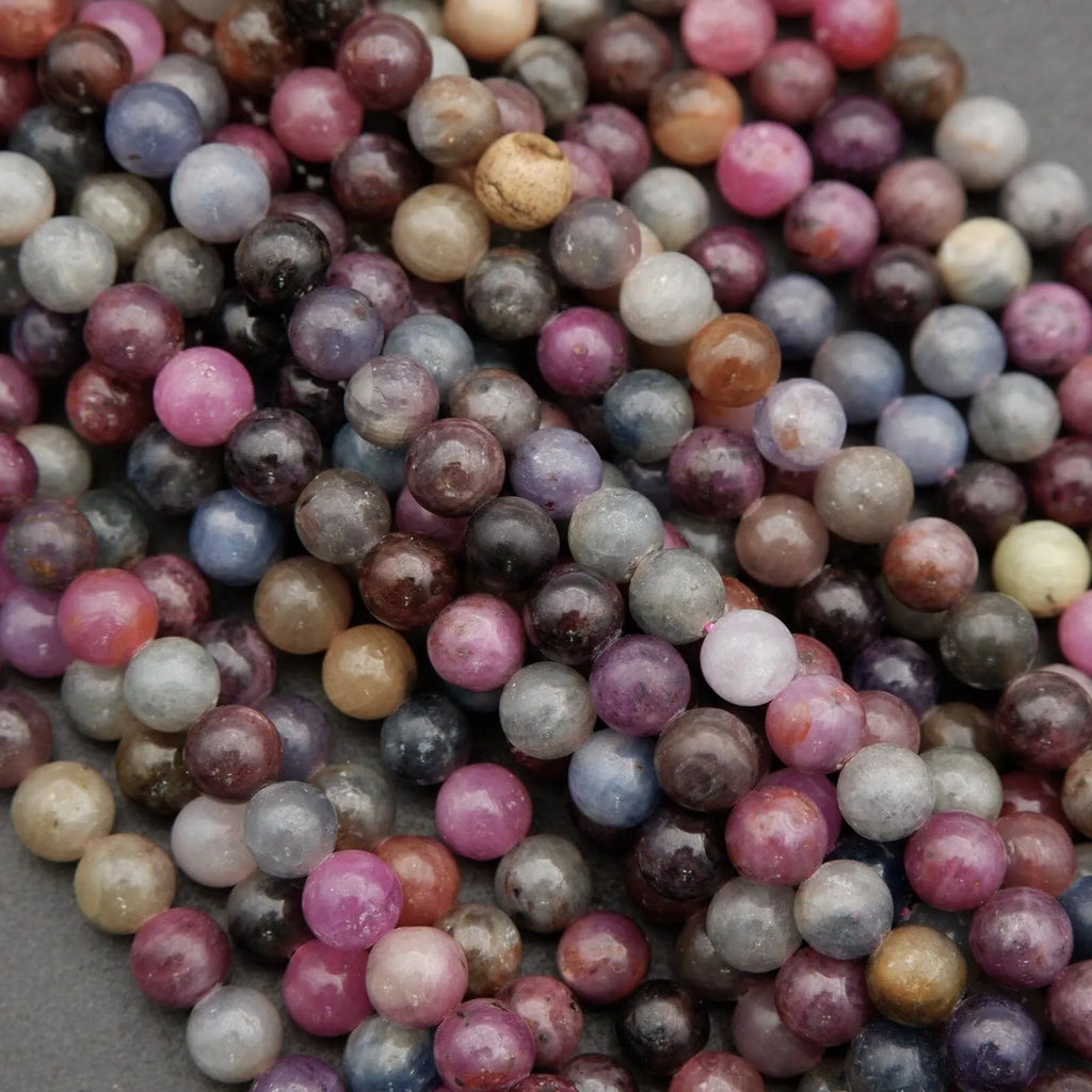 Round ruby and sapphire gemstone beads in mixed red, pink, blue, and grey tones