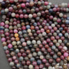 Strands of 8mm polished ruby and sapphire beads with visible inclusions and color zoning