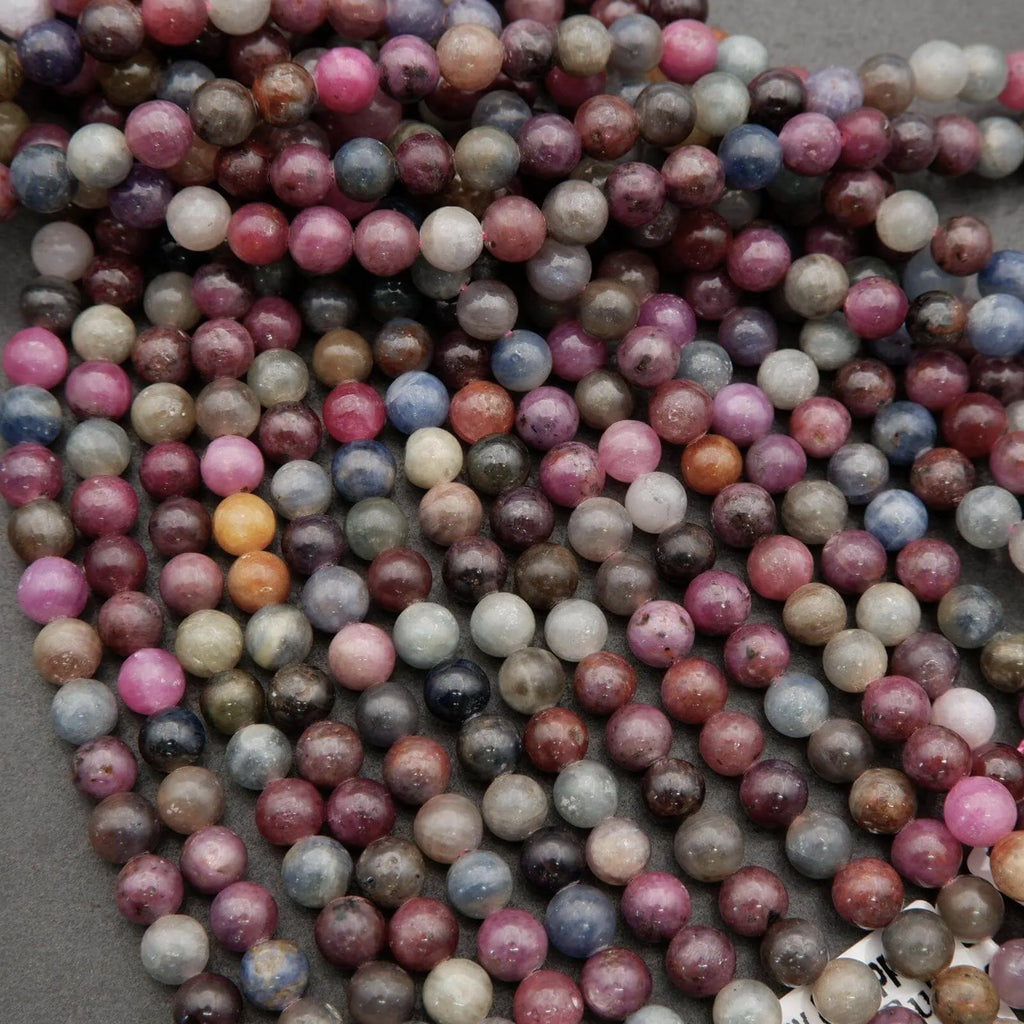 Strands of 8mm polished ruby and sapphire beads with visible inclusions and color zoning
