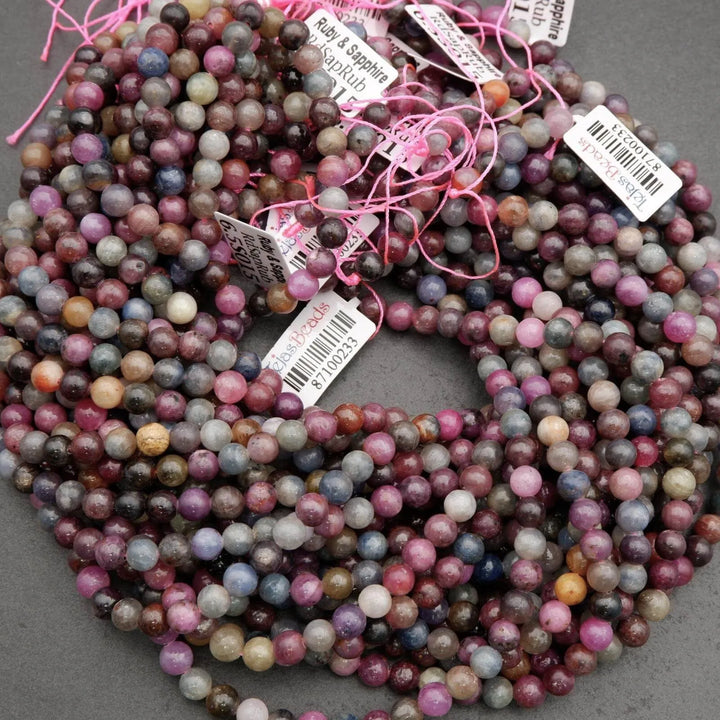 Multicolored corundum beads showing ruby reds, sapphire blues, and smoky greys