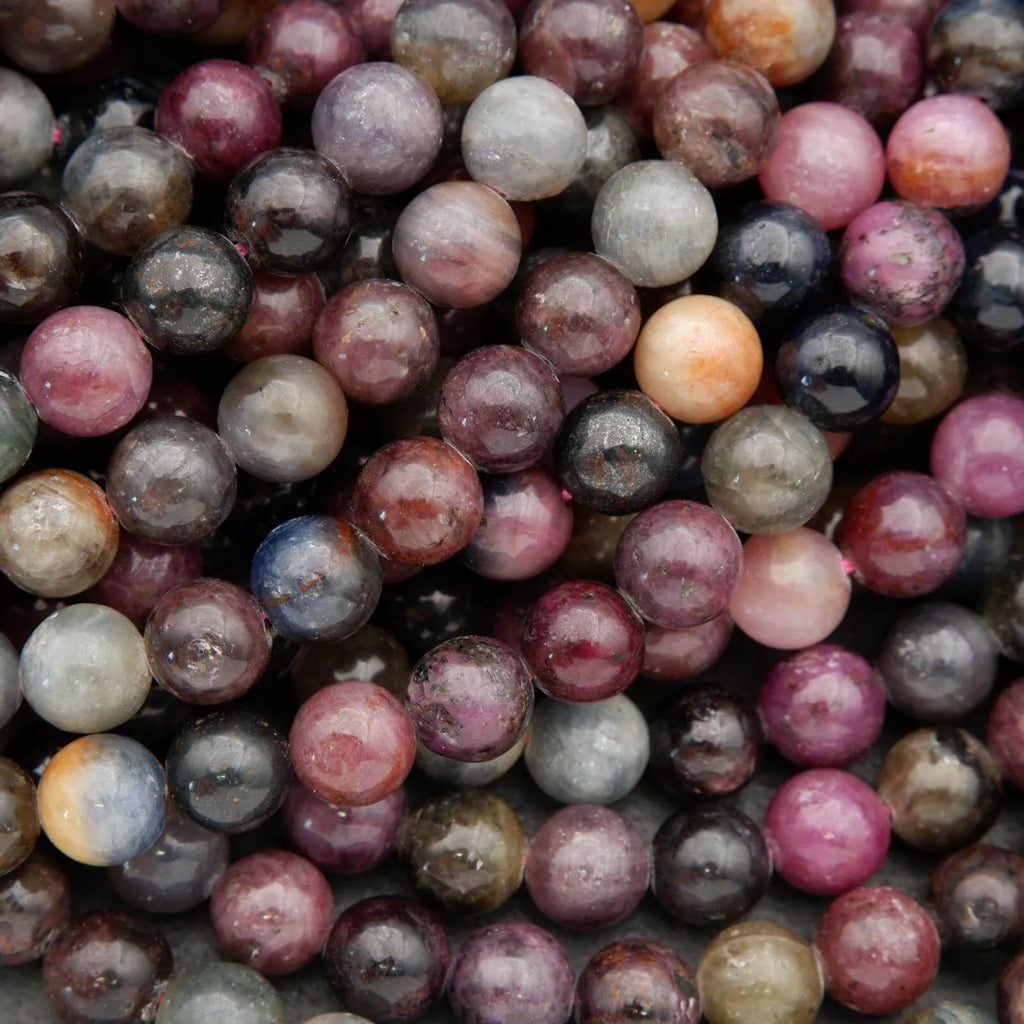 Round ruby and sapphire gemstone beads in mixed red, pink, blue, and grey tones