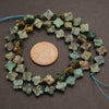 String of greenish-blue flower-shaped beads with a penny for scale on a brown background