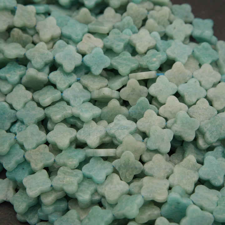 Close-up of blue clover-shaped beads on a dark surface.