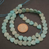String of heart-shaped turquoise beads with a penny for scale on a dark surface