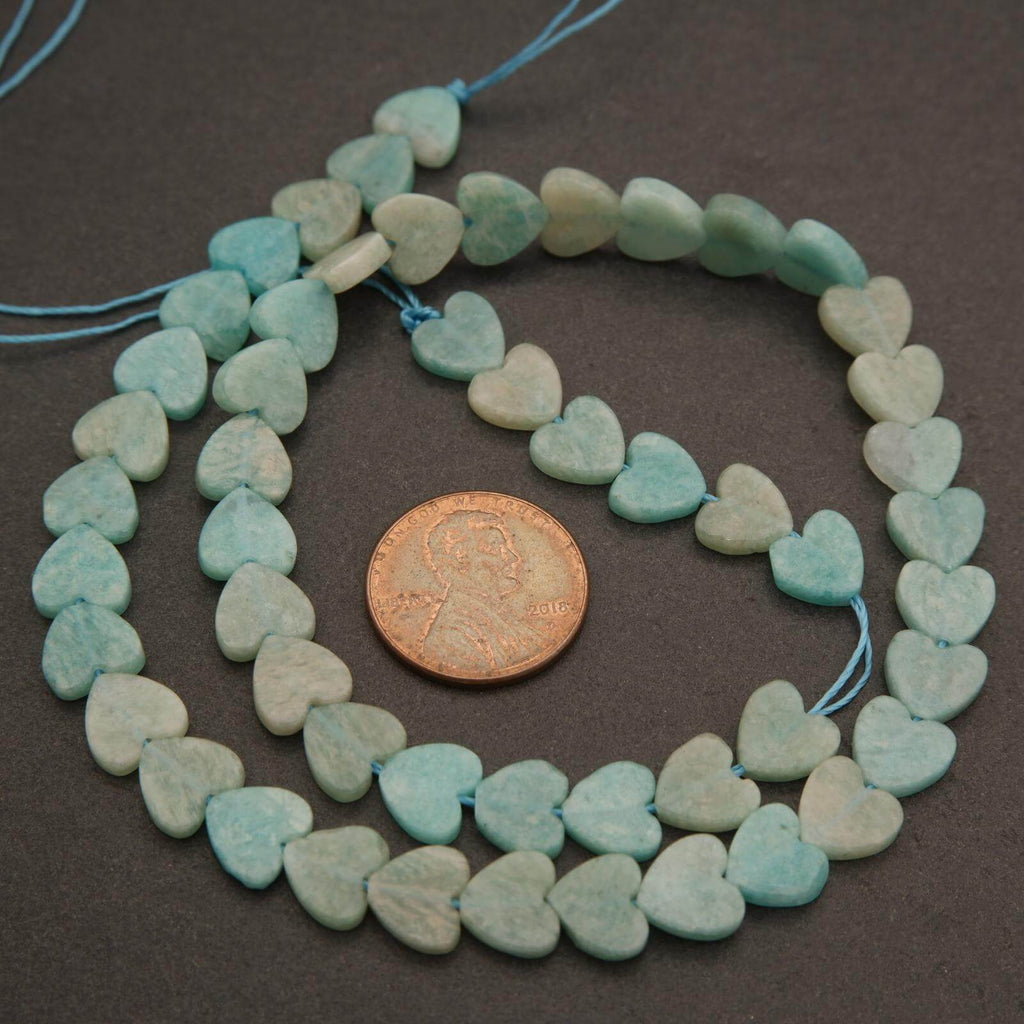 String of heart-shaped turquoise beads with a penny for scale on a dark surface