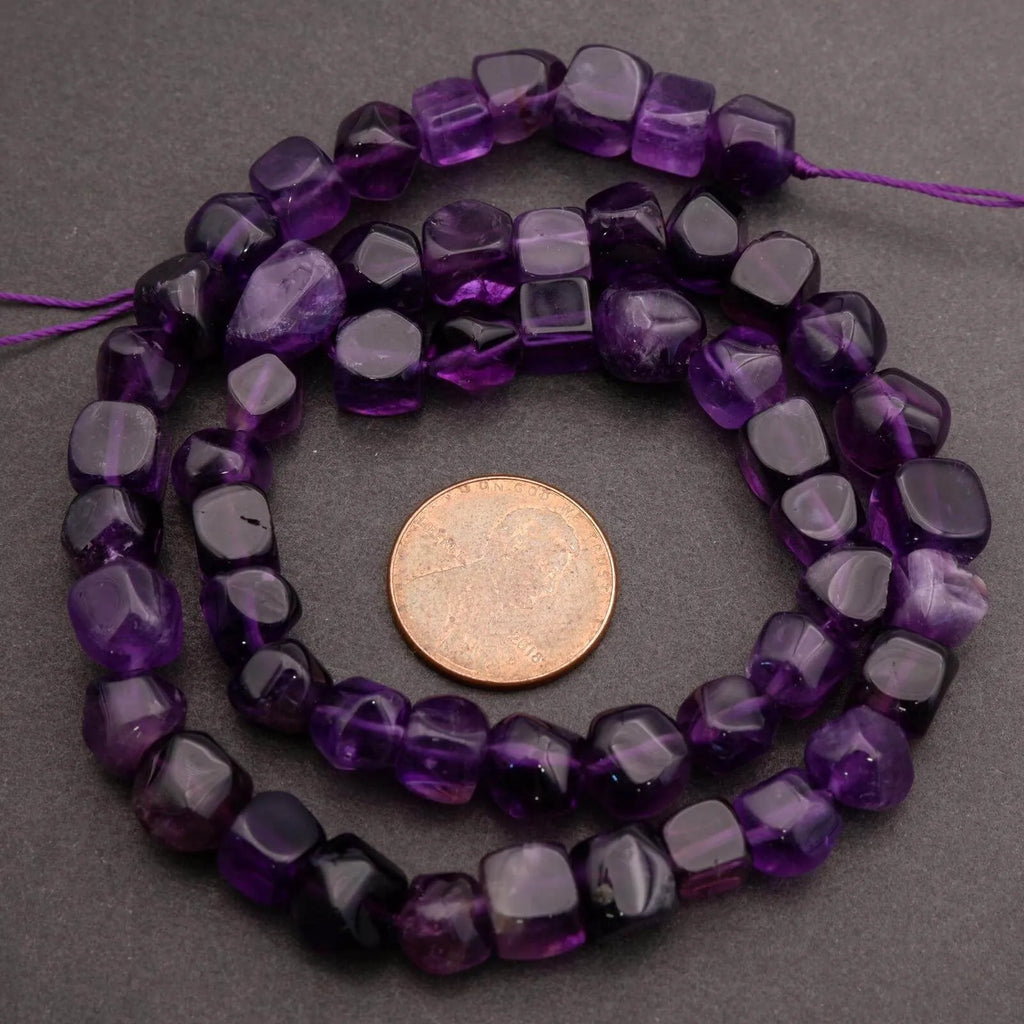 Purple beaded necklace with a coin for scale on a gray background