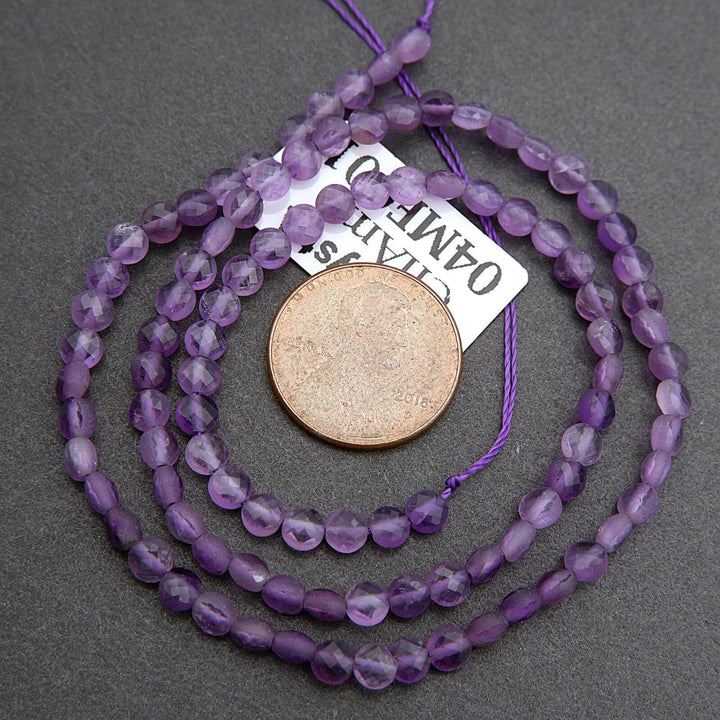 Purple beaded necklace with a coin for scale on a gray background