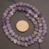 Necklace of heart-shaped purple beads with a penny for scale on a gray background
