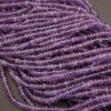 Close-up of a string of purple beads on a gray background