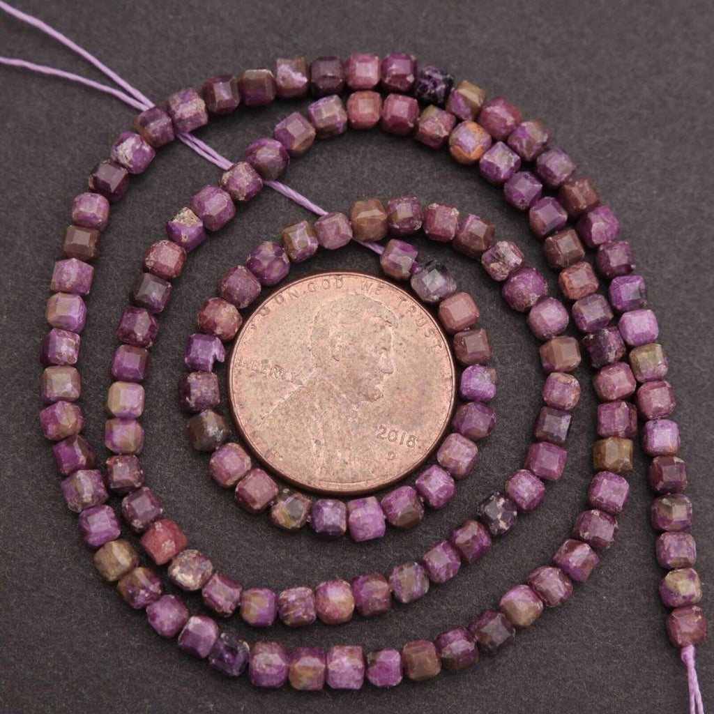 String of purple beads with a coin for size comparison on a dark background