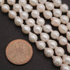 Pearl strands with a coin for size comparison on a dark surface