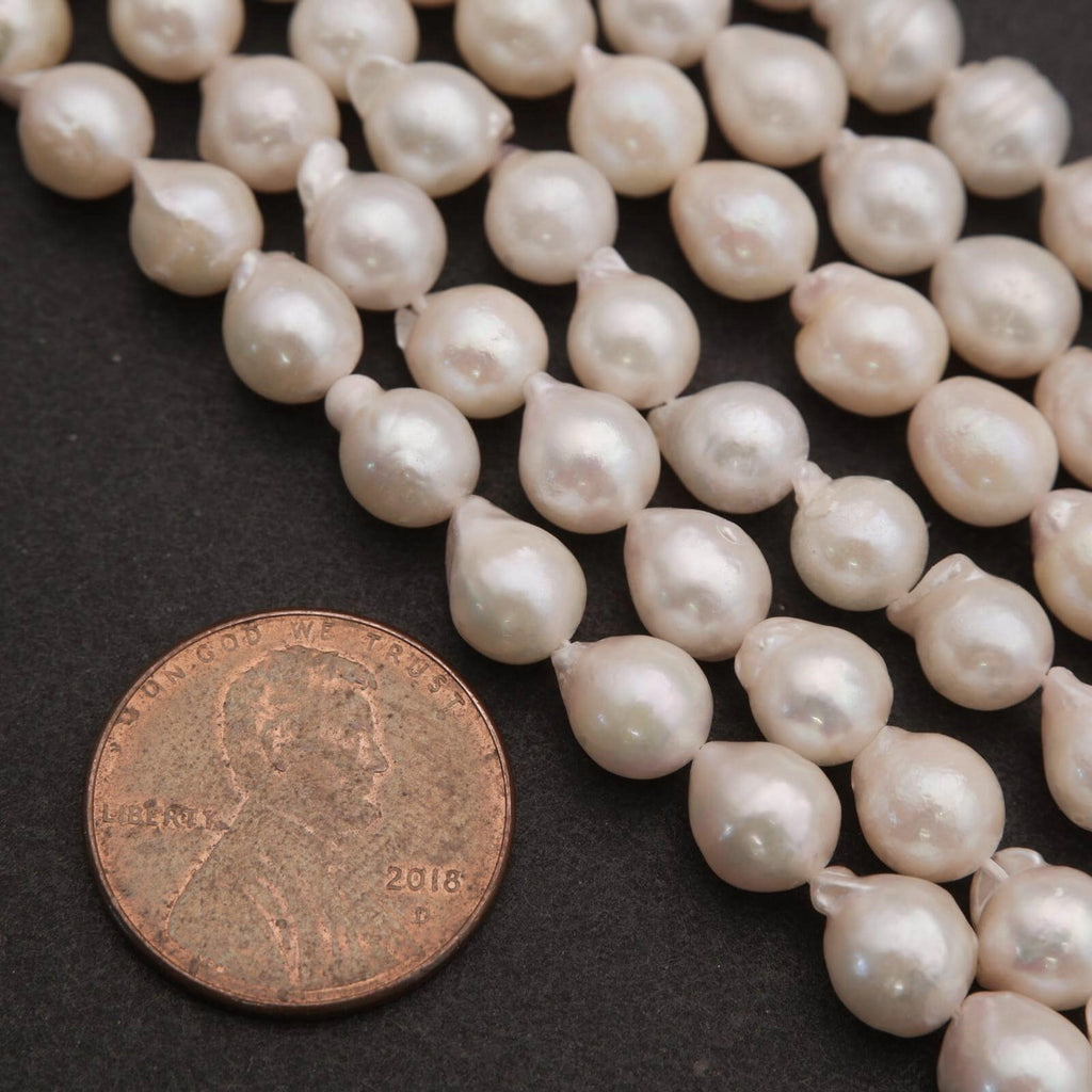 Pearl strands with a coin for size comparison on a dark surface