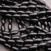 Close-up of black oval beads on a light gray background