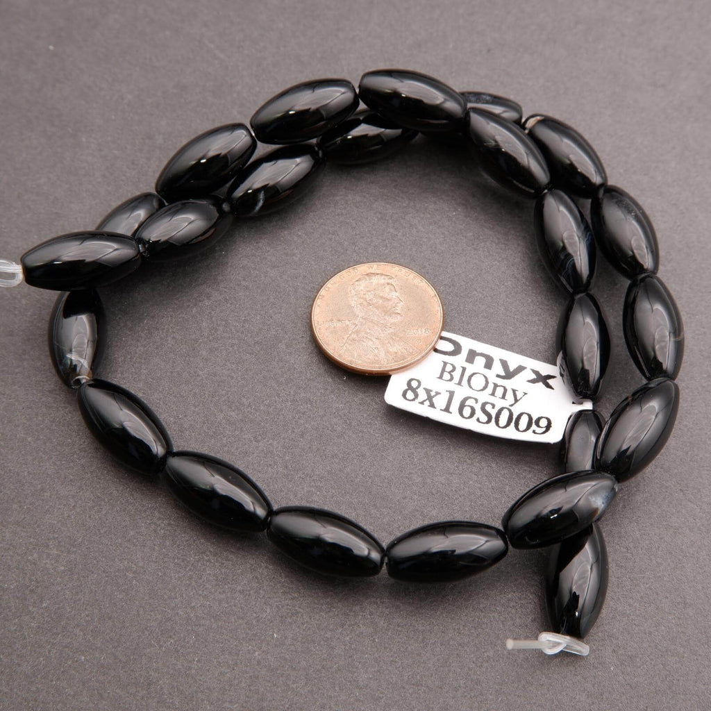 Black beaded bracelet with a coin for scale on a gray background
