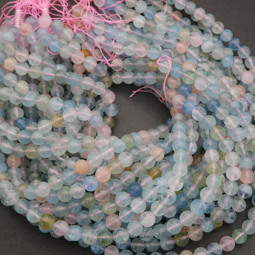 Multicolored beads on a string with pink thread against a dark background