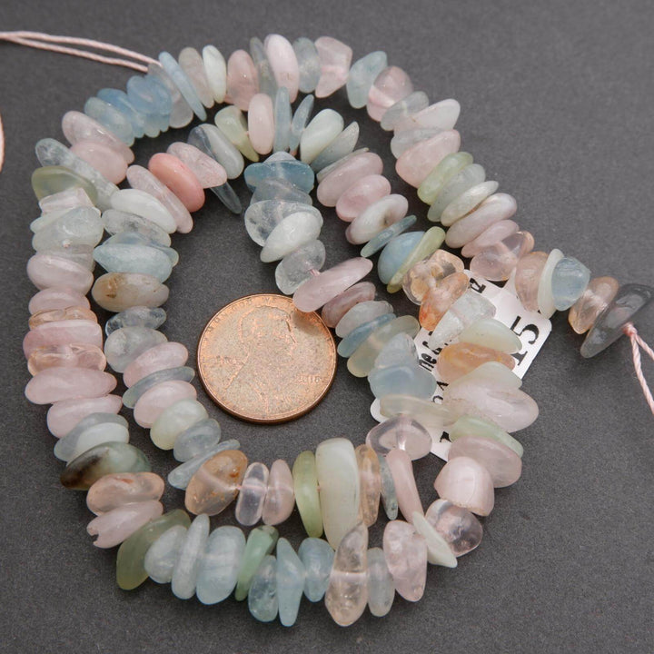 Necklace with multicolored beads and a penny for scale on a gray background