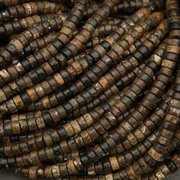 Polished biotite heishi beads in brown, black, and tan earth tones displayed on a neutral background.