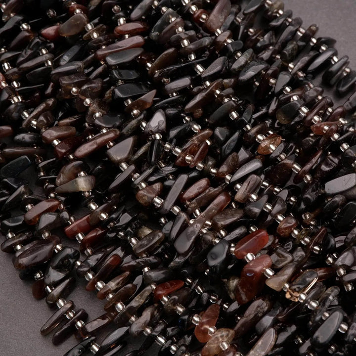 Necklace made of dark beads on a gray background