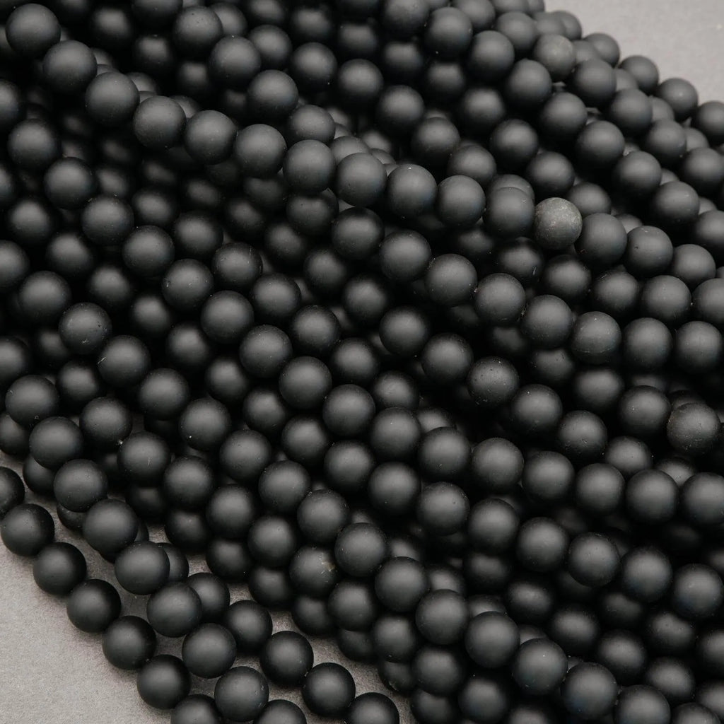 Close-up of black beads arranged in a row on a light gray background