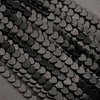 Close-up of black heart-shaped beads on a gray background