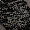 Close-up of black heart-shaped sequins on a textured surface
