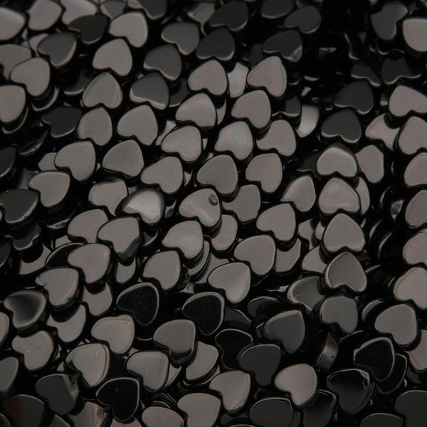Close-up of black heart-shaped beads on a black background