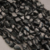 Close-up of dark metallic beads on a textured surface