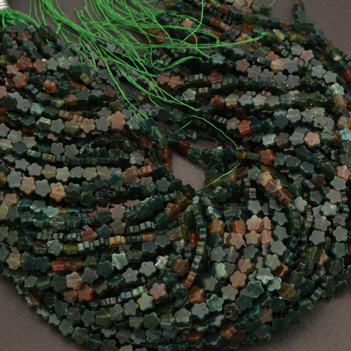 Close-up of a string of multicolored beads on a green thread.