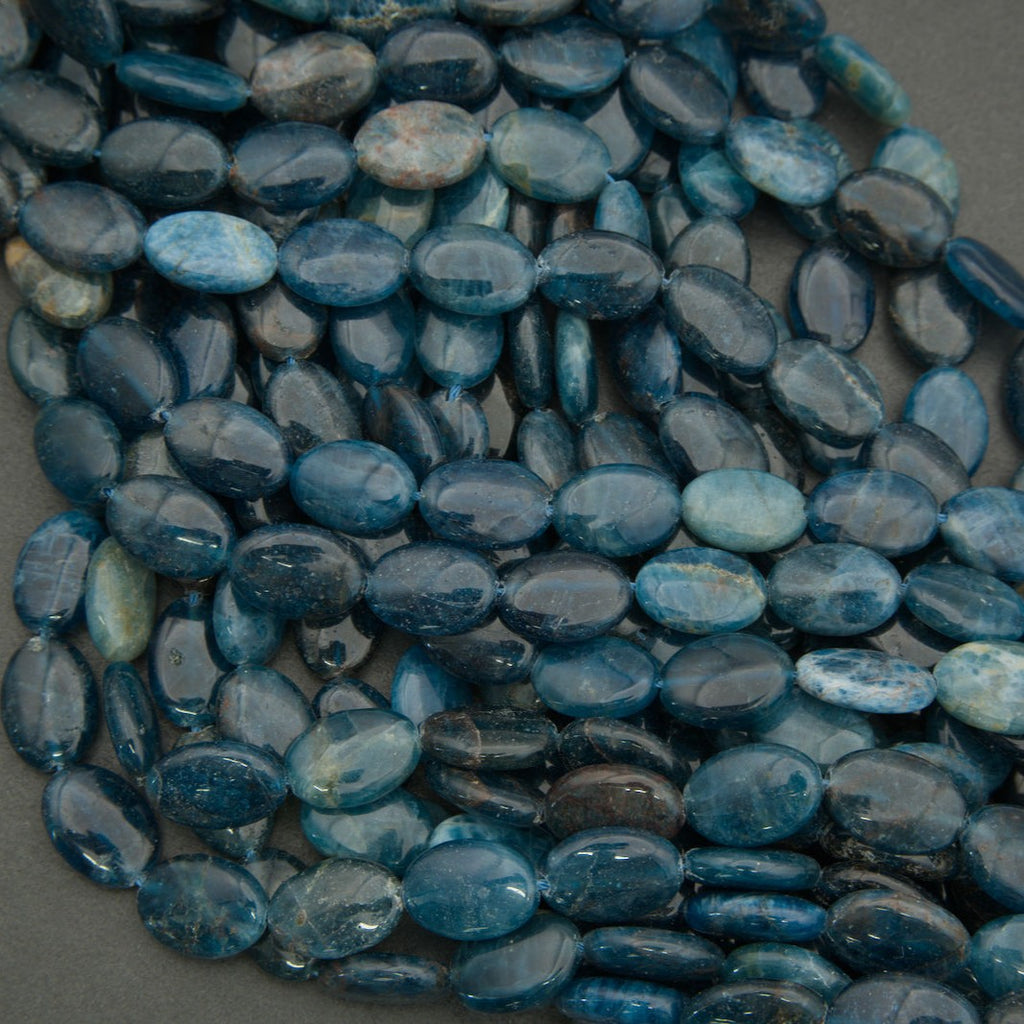Detailed view of polished blue apatite oval beads with natural inclusions and color zoning.