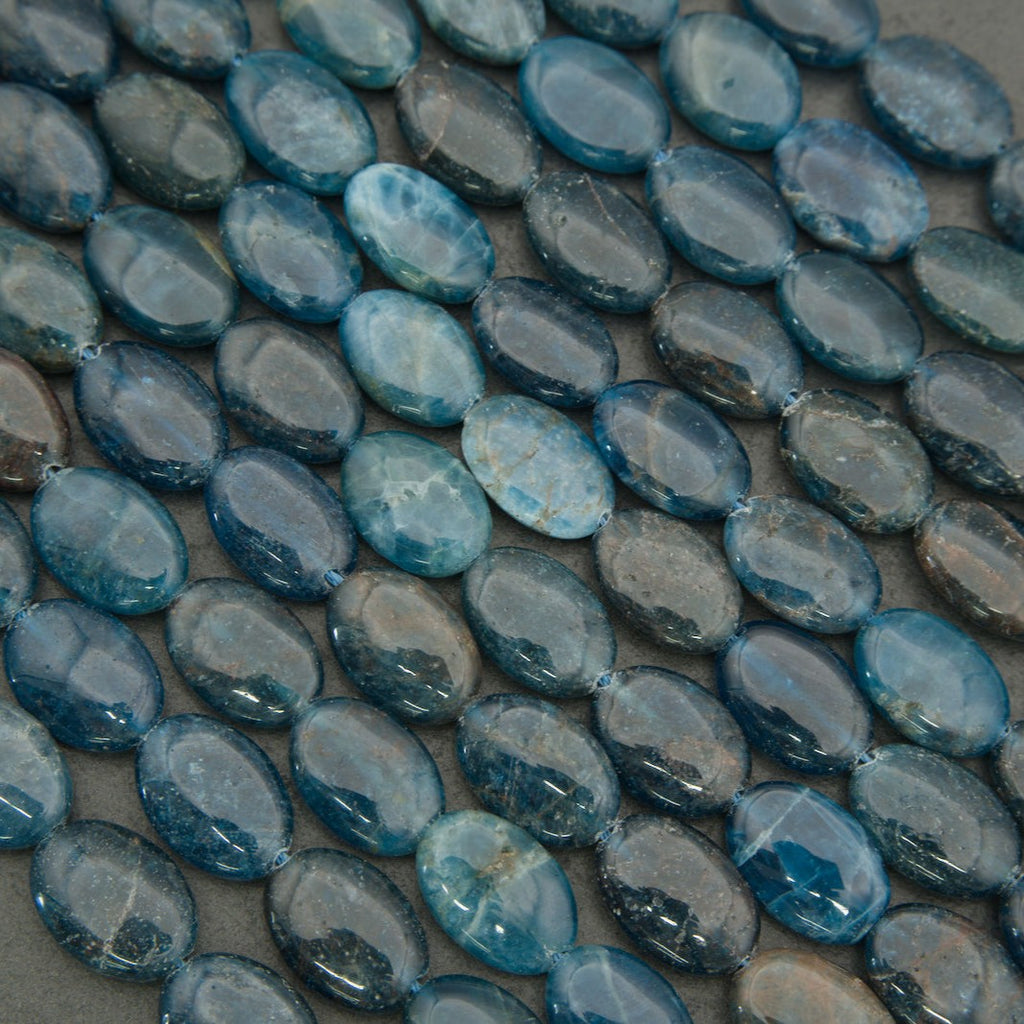 Natural blue apatite oval bead strands arranged in a circular layout on a neutral background.