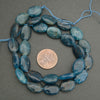 Close-up of polished blue apatite beads showing varied shades of blue and organic patterns.