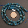 Blue glass beads with a penny for scale on a gray background