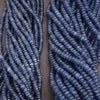 Two strands of blue beads on a gray background