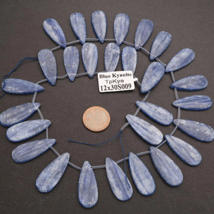 Blue kyanite stones arranged in a circular pattern on a dark surface with a label.