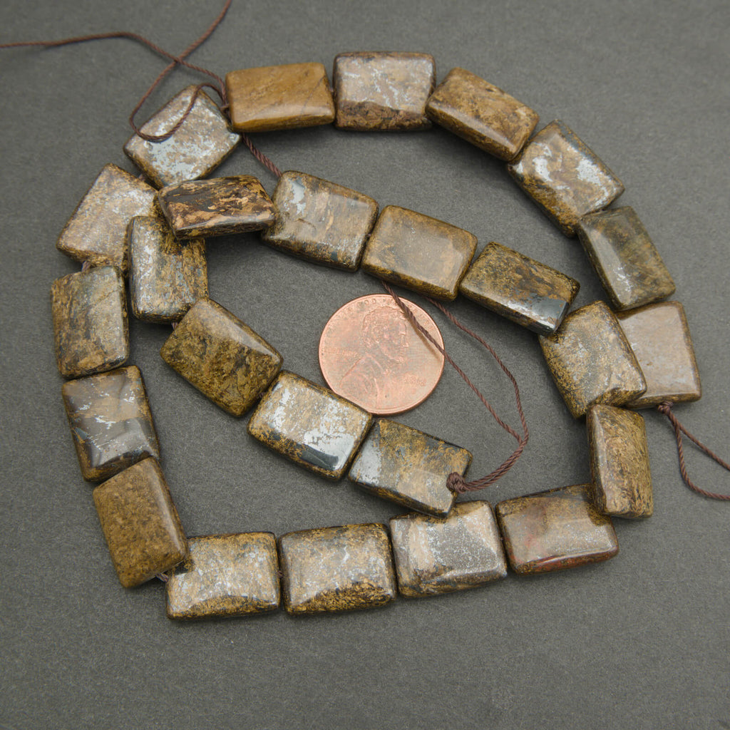 String of square-shaped beads with a penny for size comparison on a gray background