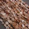 Close-up of pink and brown stone beads on a dark surface