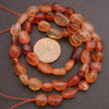 String of orange beads with a coin for size comparison on a dark surface