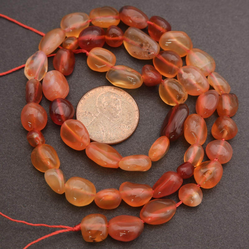 String of orange beads with a coin for size comparison on a dark surface