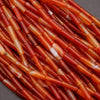 Close-up of orange and red cylindrical beads on a dark background