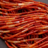 Close-up of red and orange stone beads on a gray background