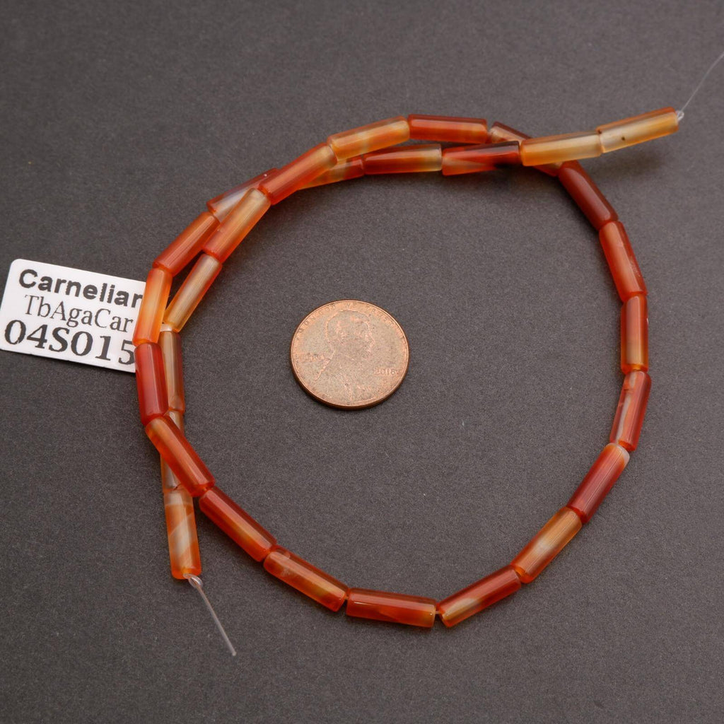 Carnelian bead necklace with a penny for scale on a gray background