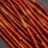 Close-up of red and orange cylindrical beads on a dark background