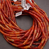 Coiled string of red and orange beads with visible labels on a gray background