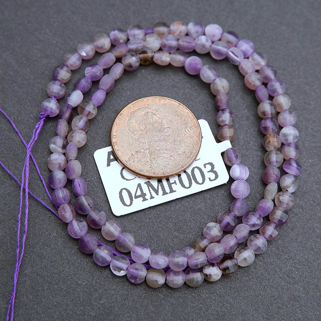 String of purple beads with a coin for scale on a gray background
