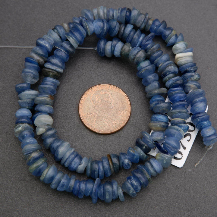 String of blue beads with a penny for scale on a gray background