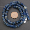 String of blue beads with a penny for scale on a gray background